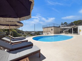 Una piscina al aire libre, sillones reclinables de piscina