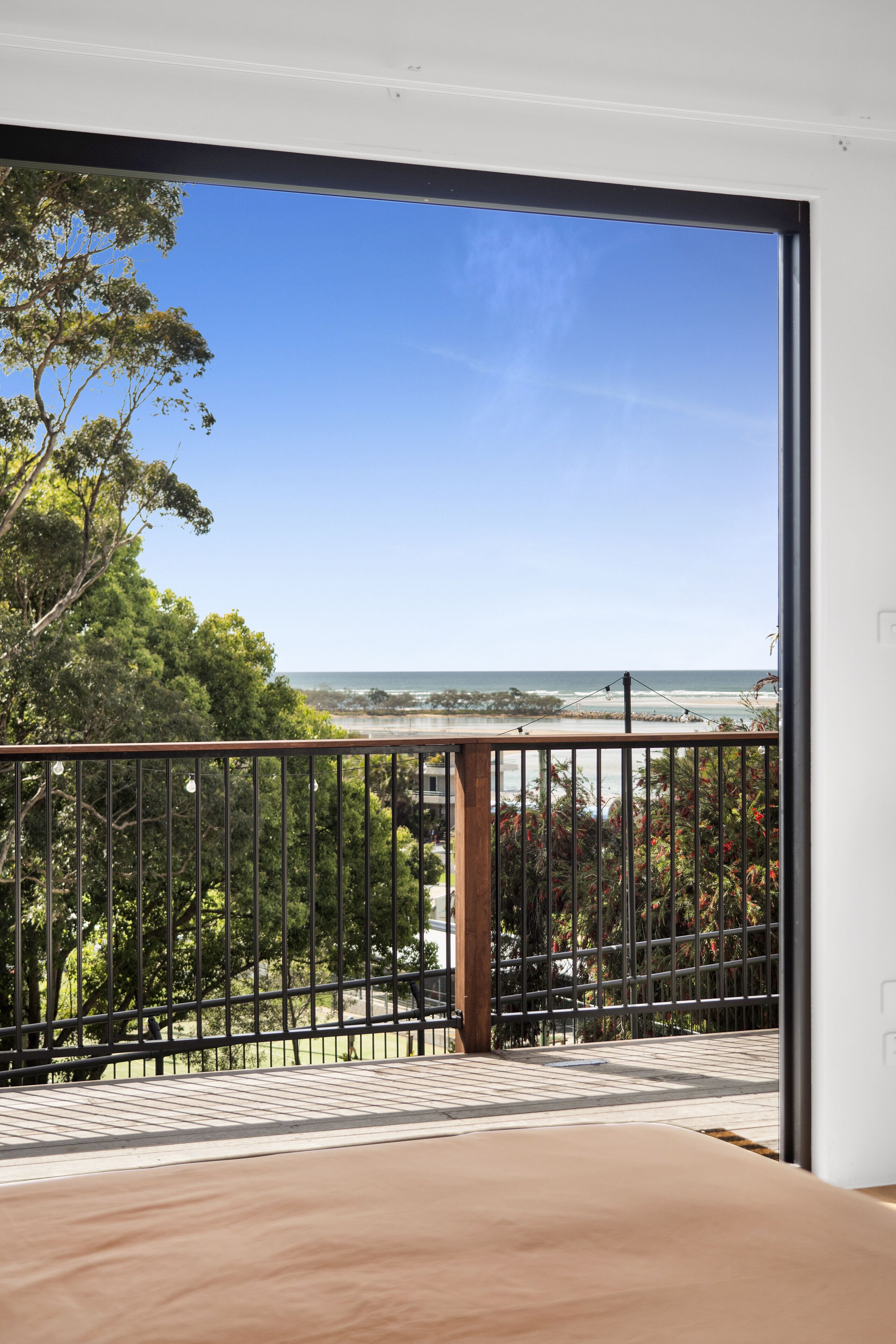 Un balcon offrant une vue dégagée sur l’océan et les arbres.