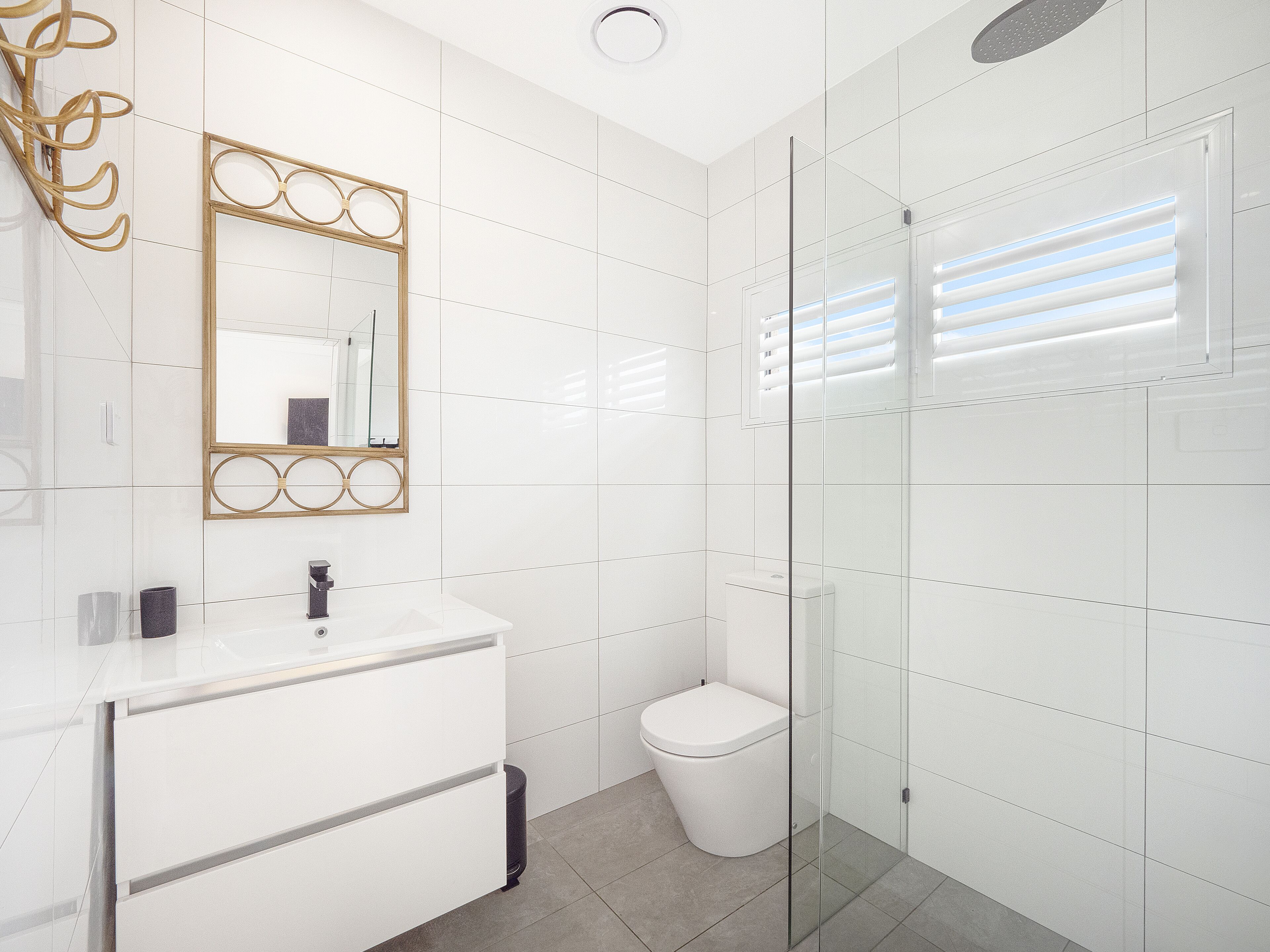 A modern bathroom with a white vanity, a toilet, and a glass-enclosed shower.