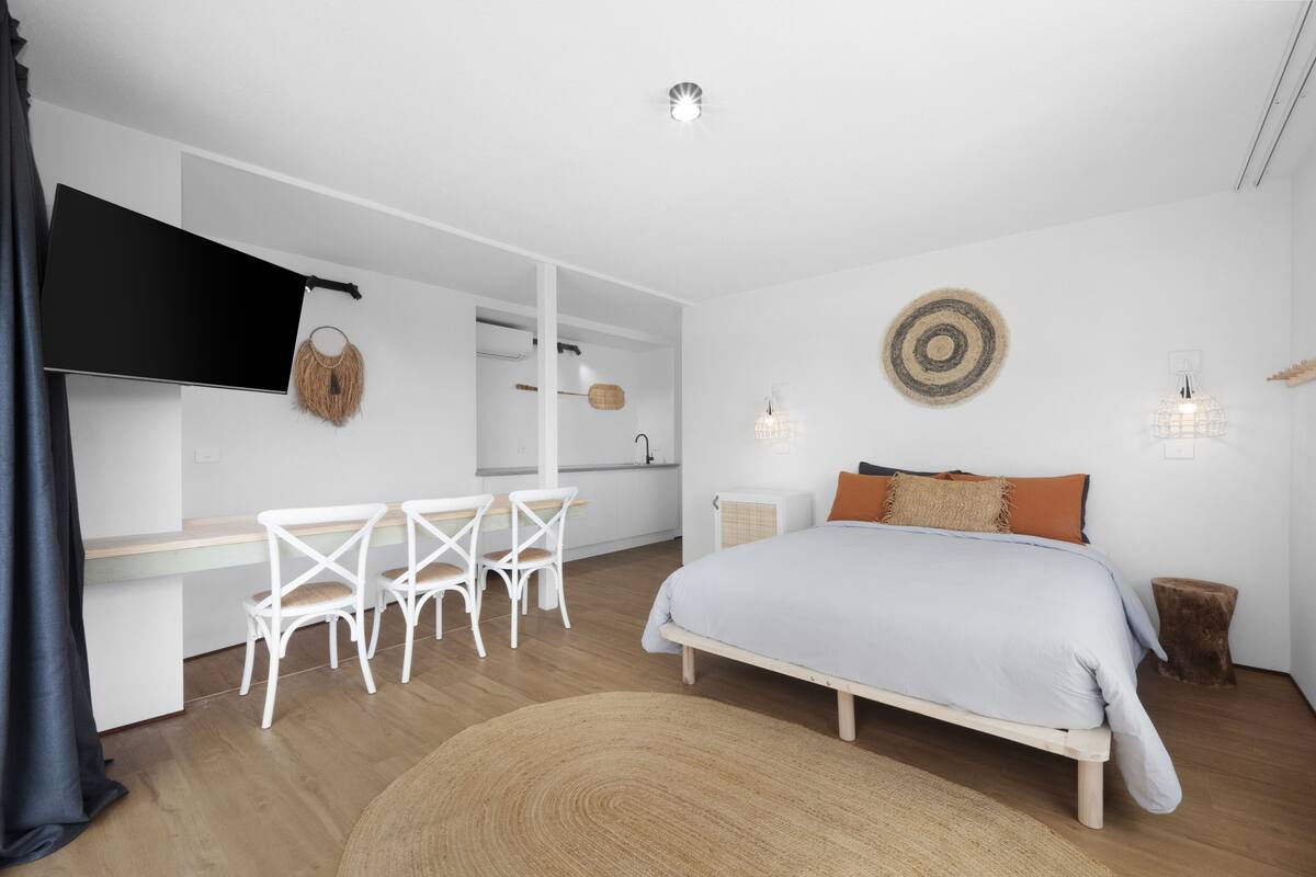 A modern bedroom with a bed, a desk, and chairs.