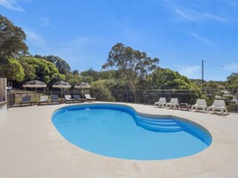 Una piscina al aire libre, sillones reclinables de piscina