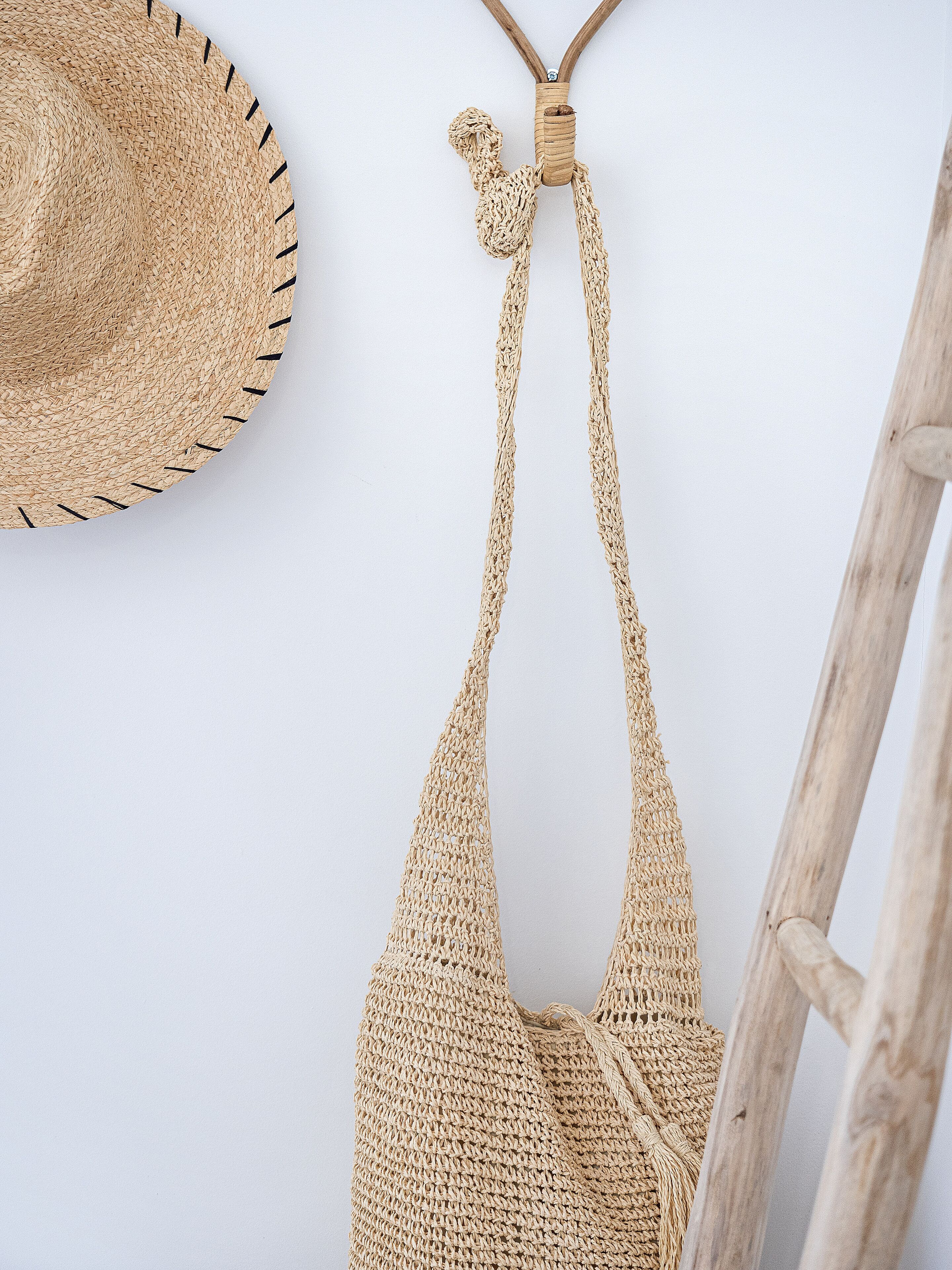 A straw hat and a woven bag hanging on a wall.