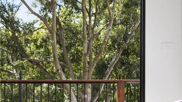 Un balcon donnant sur un arbre, avec une table et une chaise.