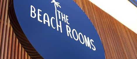 Een bordje met de tekst 'The Beach Rooms' en een palmboom symbool.