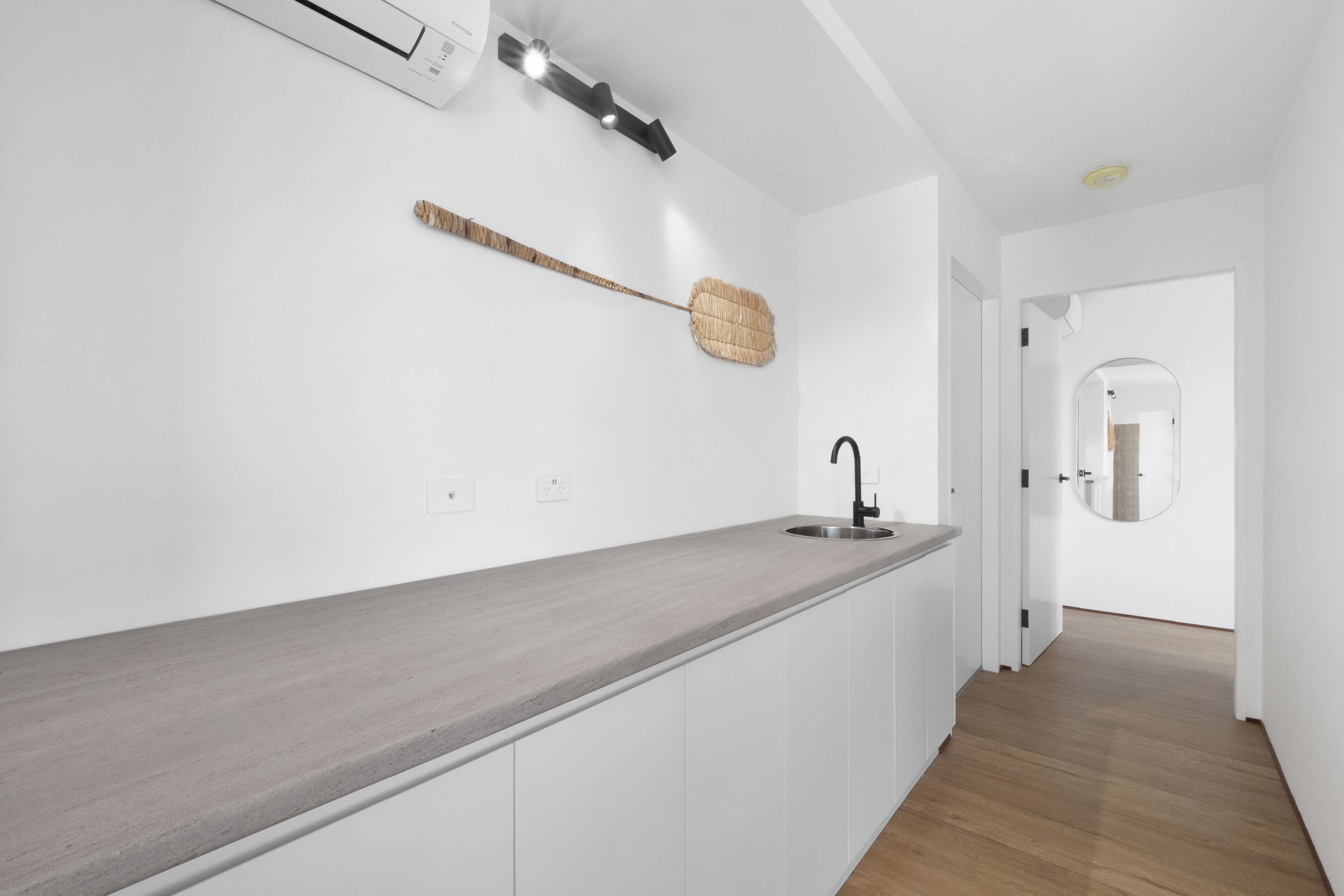 A modern kitchen with a long countertop, a sink, and a wall-mounted basket.