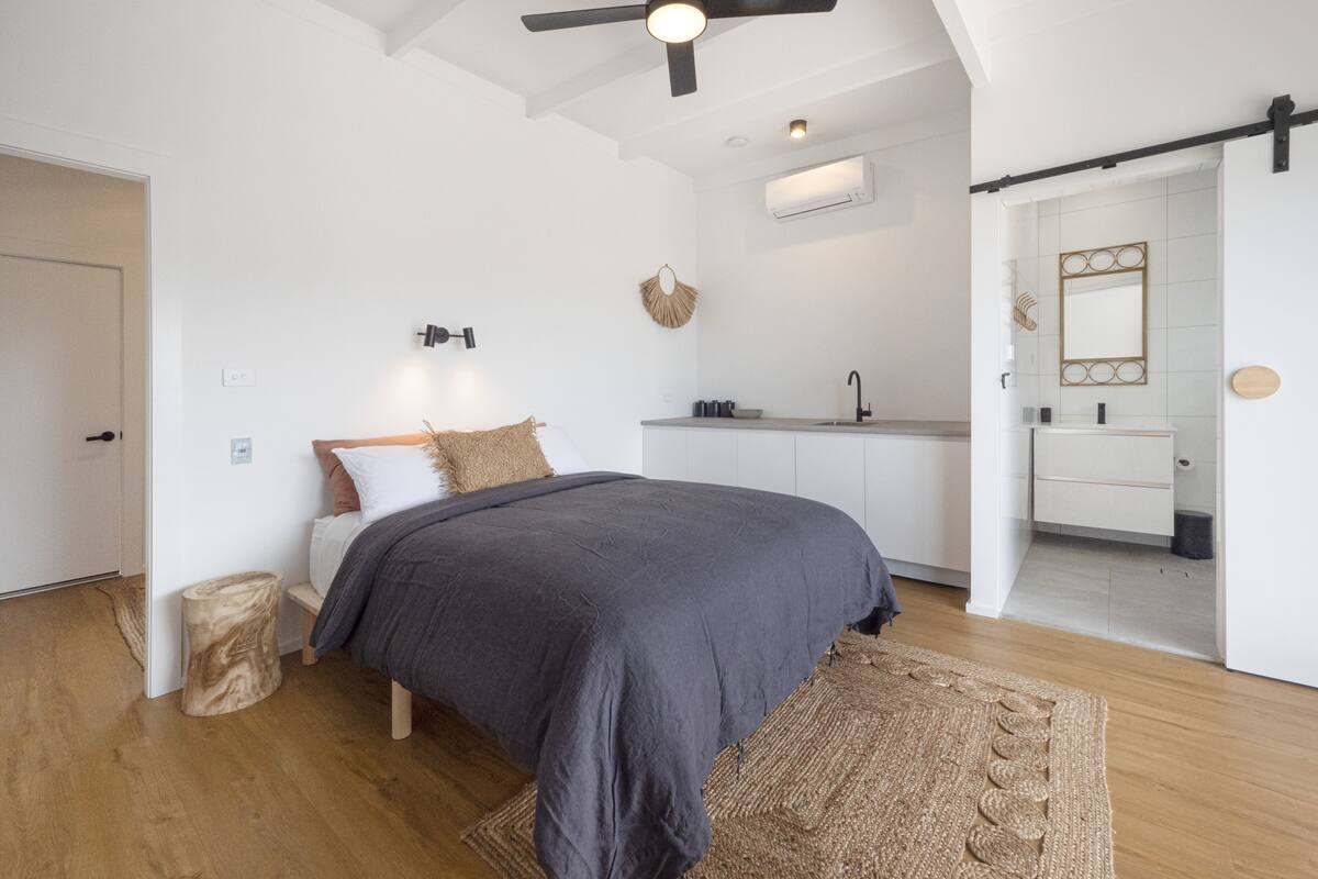 A modern bedroom with a bed, bedside table, and a large window.