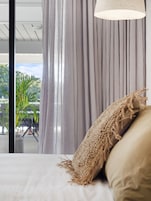 Un dormitorio con cama, ventana con cortinas y vista a zonas verdes.