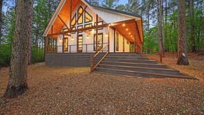 Een chalet met een steil dak, grote ramen en een overdekte veranda.