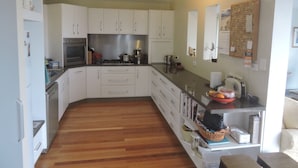 A compact kitchen with white cabinets, a stainless steel oven, and a wooden floor.