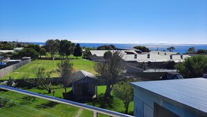 A residential area with houses, a grassy field, and a view of the ocean.