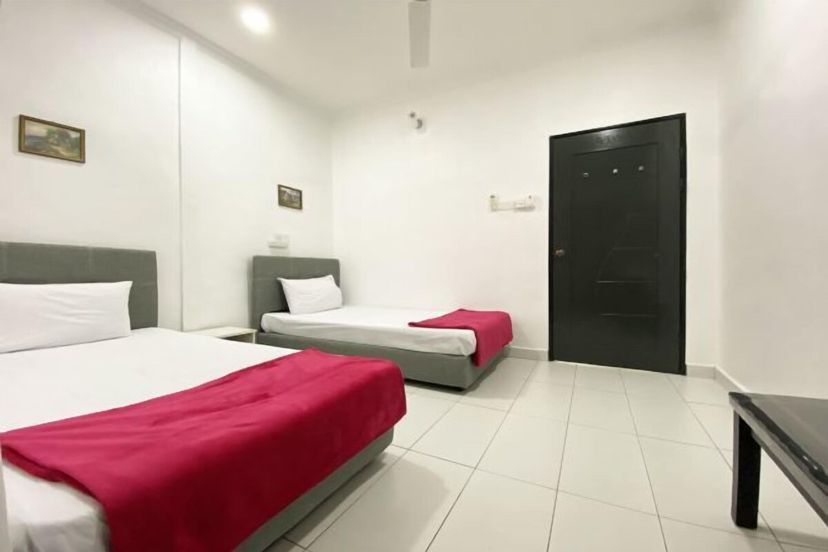 Ett hotellrum med två sängar, en svart dörr och ett litet bord.