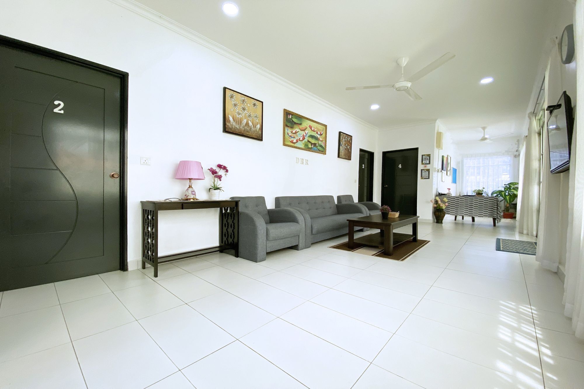 A modern living room with a grey sofa, a coffee table, and a lamp. There are three paintings on the wall and a door labeled '2'.