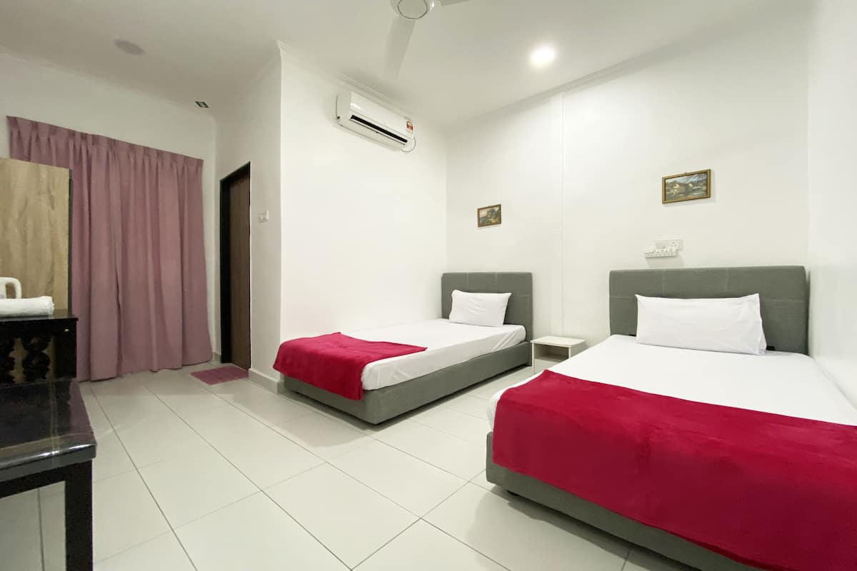 Habitació d'hotel amb dos llits, un escriptori, aire condicionat i una finestra amb cortines.