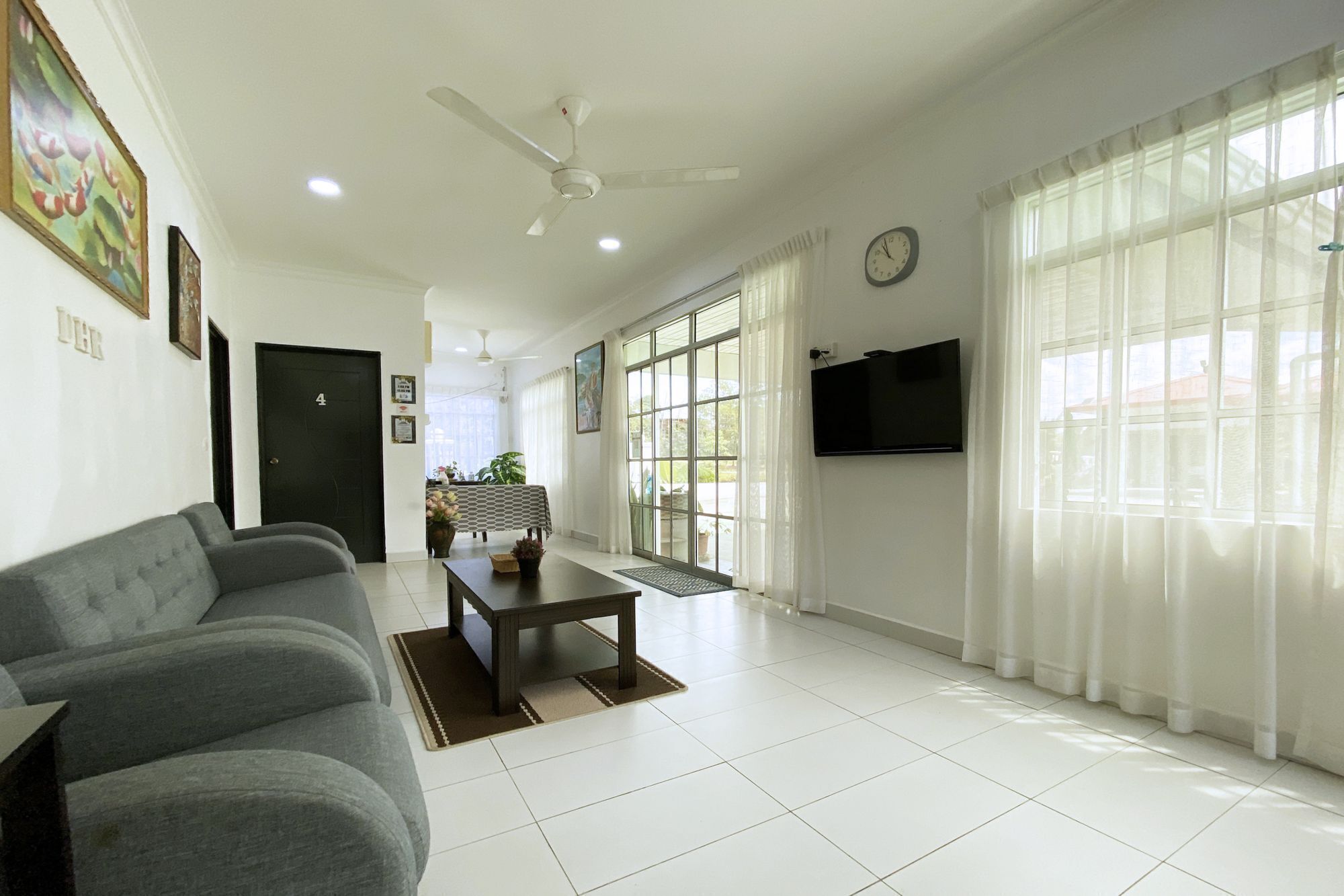A living room with a sofa, a coffee table, a TV, and a large window with curtains.