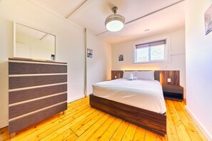 Relax in this serene bedroom with a large bed and a dresser, offering a peaceful view of the outdoors.
