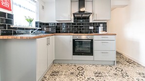 A modern kitchen with white cabinets, a black tiled backsplash, a built-in oven, and a patterned floor.