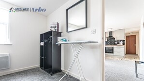 A hotel room with a kitchenette, a hairdryer, and an ironing board.