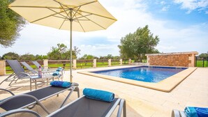 A swimming pool with lounge chairs and an umbrella. - Holiday Home "Can Cuixa" with Pool, Wi-Fi, Air Conditioning & Garden (Santa Margarita)