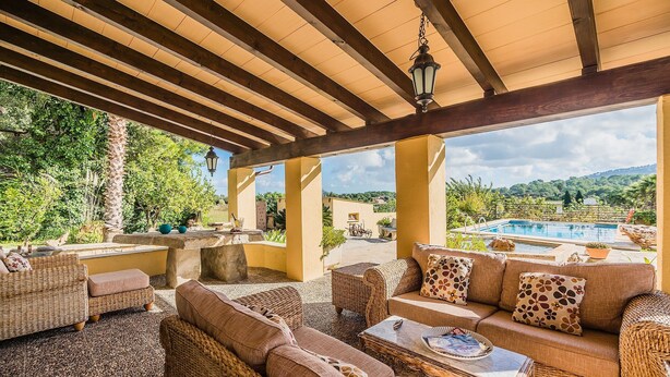 Une terrasse extérieure aménagée avec des meubles en osier, une piscine et une vue sur le paysage.