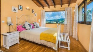Une chambre à coucher avec un lit, une table de chevet, une lampe et une fenêtre donnant sur un beau paysage.