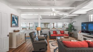 A spacious living room with a large TV, comfortable seating, and a view of the outdoors. - Fun in the Sun  Gulf front, steps to the sand, 4-bed with spectacular views! (Anna Maria)
