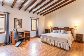 Une chambre avec un plafond en bois, un lit avec des oreillers, un bureau et une chaise.