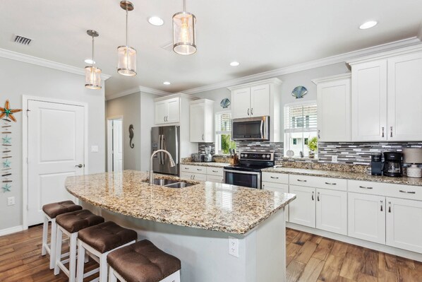 A modern kitchen with white cabinets, granite countertops, and stainless steel appliances.