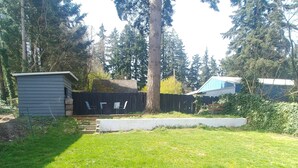 A backyard with a small shed, a wooden fence, and a grassy lawn. - Cool Mid-Century Bungalow!  (Vancouver)