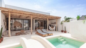 A modern outdoor pool area with lounge chairs, a hammock, and a pergola. - Yucca Villas (Canggu)