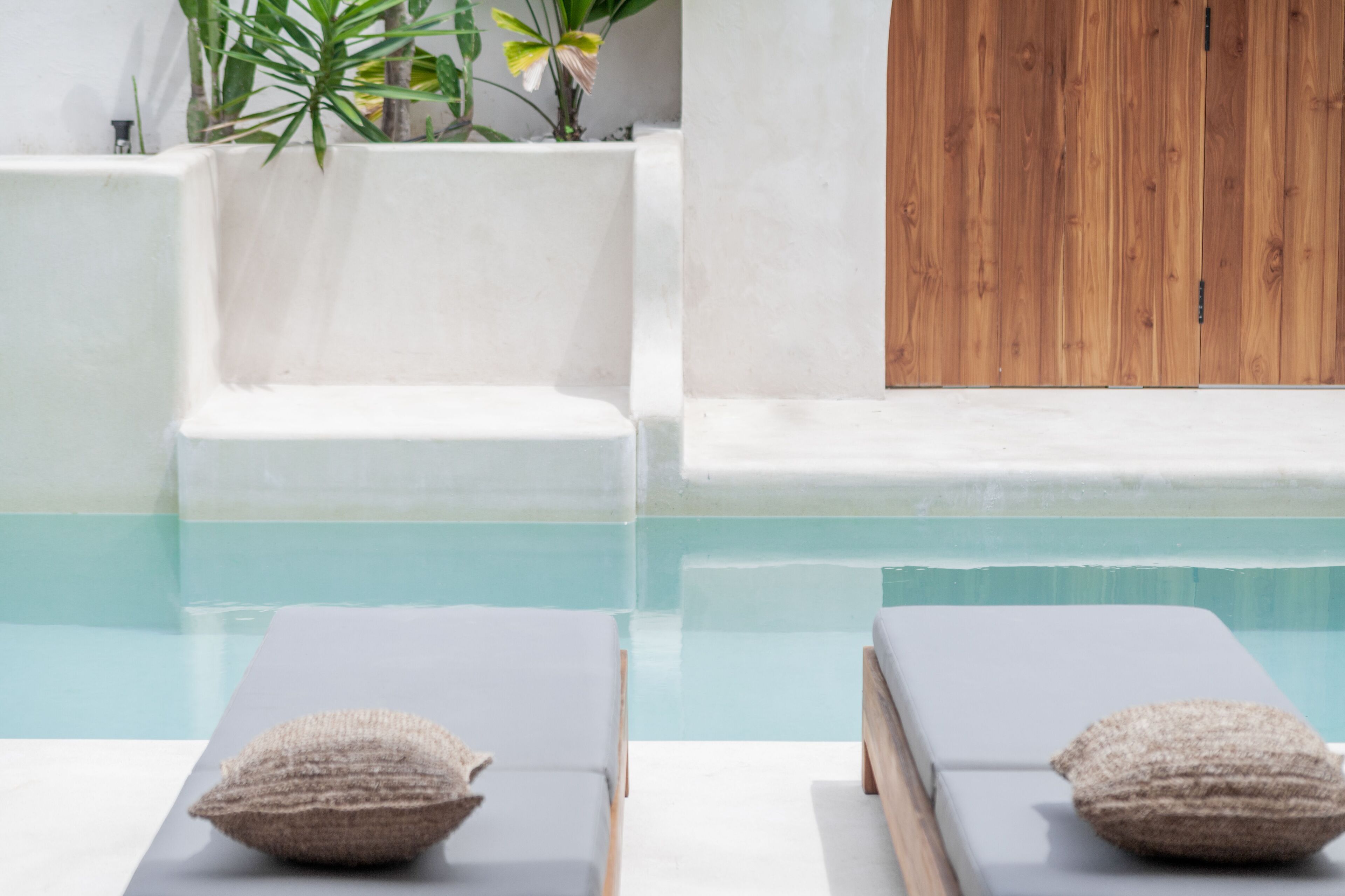 A pool area with two lounge chairs and a wooden door.