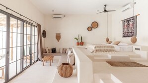 A modern, well-lit living room with a large sliding glass door, a sofa set, a coffee table, and a hanging basket. - Yucca Villas (Canggu)