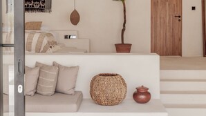 A modern living room with a sofa, a woven basket, and a potted plant. - Yucca Villas (Canggu)