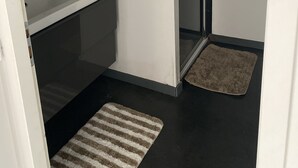 Un baño con un lavamanos blanco, un espejo, una ducha y una alfombra a rayas.