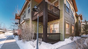 Ein zweistöckiges Haus mit Balkon und überdachter Veranda, der Hof ist mit Schnee bedeckt.