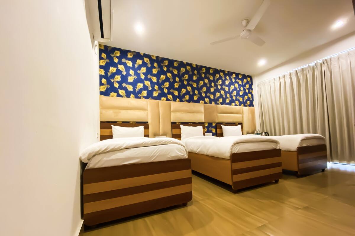 A hotel room with two beds, a ceiling fan, and a window with curtains.