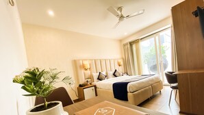 A hotel room with a bed, bedside table, lamp, and a potted plant. - Sky Suites Huda City Center (Gurugram)