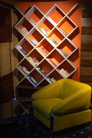 Un sillón amarillo frente a una estantería llena de libros.