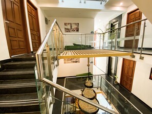 Un interior moderno con barandilla de cristal, escaleras negras y puertas de madera.