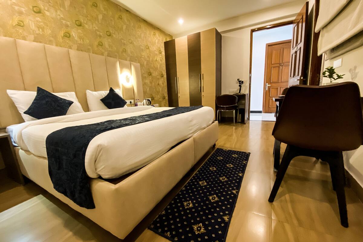 A hotel room with a bed, bedside table, chair, and a desk.