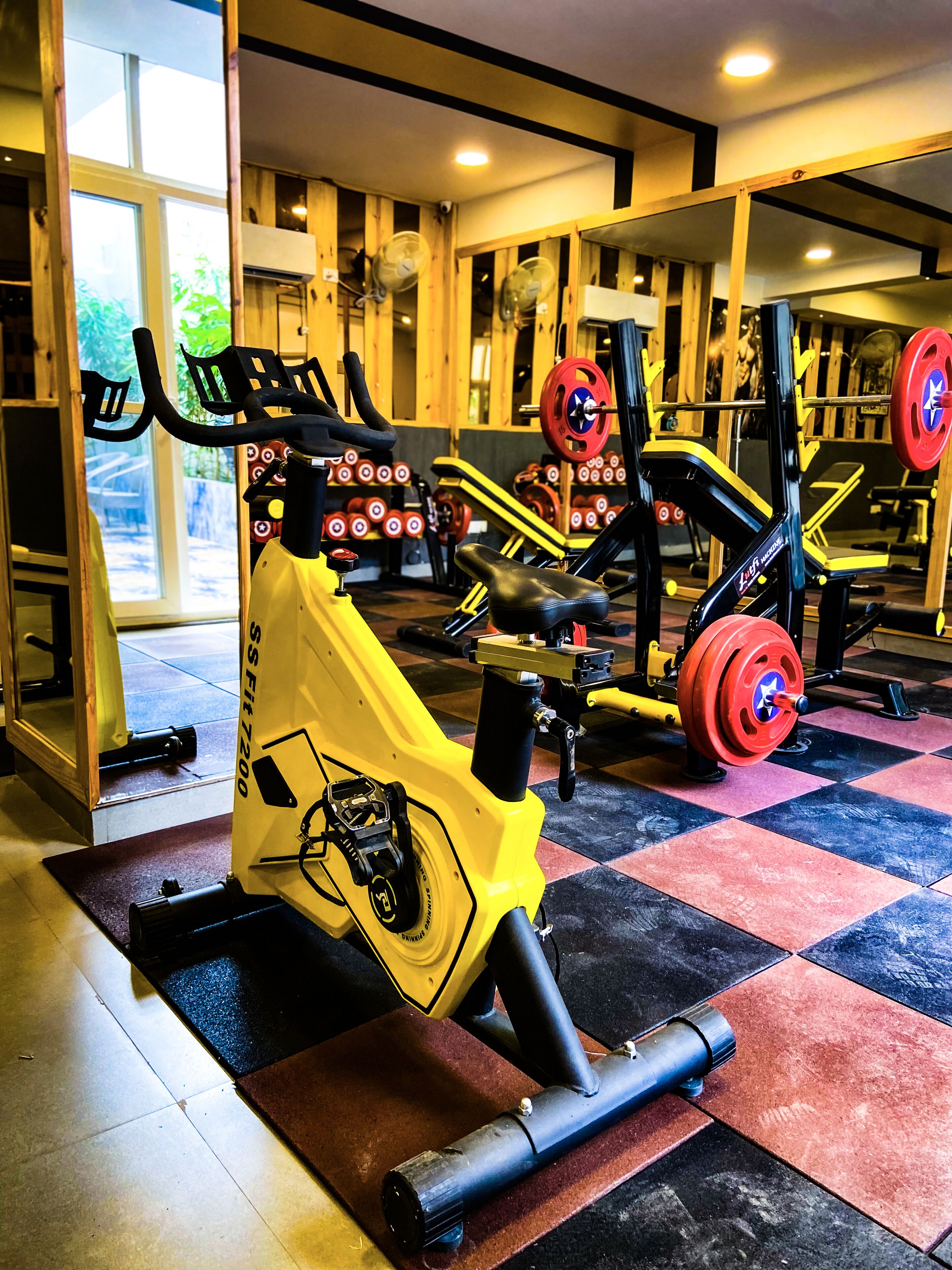 A gym with exercise equipment, a mirror, and a checkered floor.