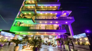 A multi-story hotel with a modern design, featuring balconies and a well-lit entrance. - Sky Suites Huda City Center (Gurugram)