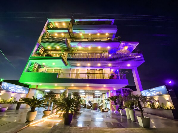 Un hotel de varios pisos con un diseño moderno, que cuenta con balcones y una entrada bien iluminada.