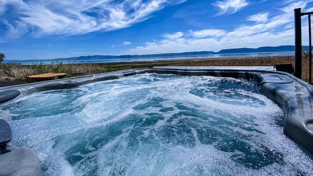 Ein Whirlpool mit Blick auf eine natürliche Landschaft und Berge in der Ferne.
