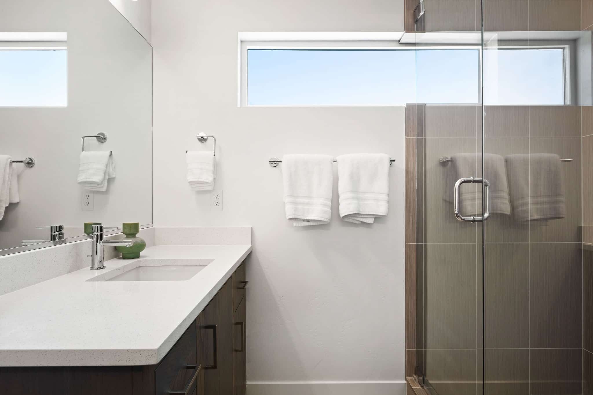 Une salle de bain moderne avec un grand miroir, un lavabo et une douche à parois de verre.