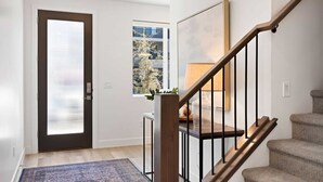 A staircase with wooden steps and black railings, leading to a landing with a window and a door with blinds. - Family Paradise at the Vue by RedAwning (St. George)