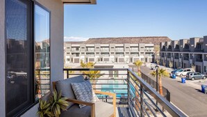 A balcony with a view of a swimming pool, a building in the background, and a parked car. - Family Paradise at the Vue by RedAwning (St. George)