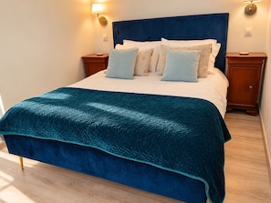 Un letto con una testiera blu, diversi cuscini e una coperta verde acqua.