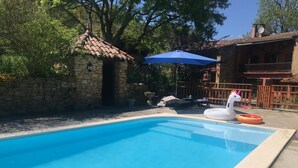 A swimming pool with a swan float and a sun umbrella.