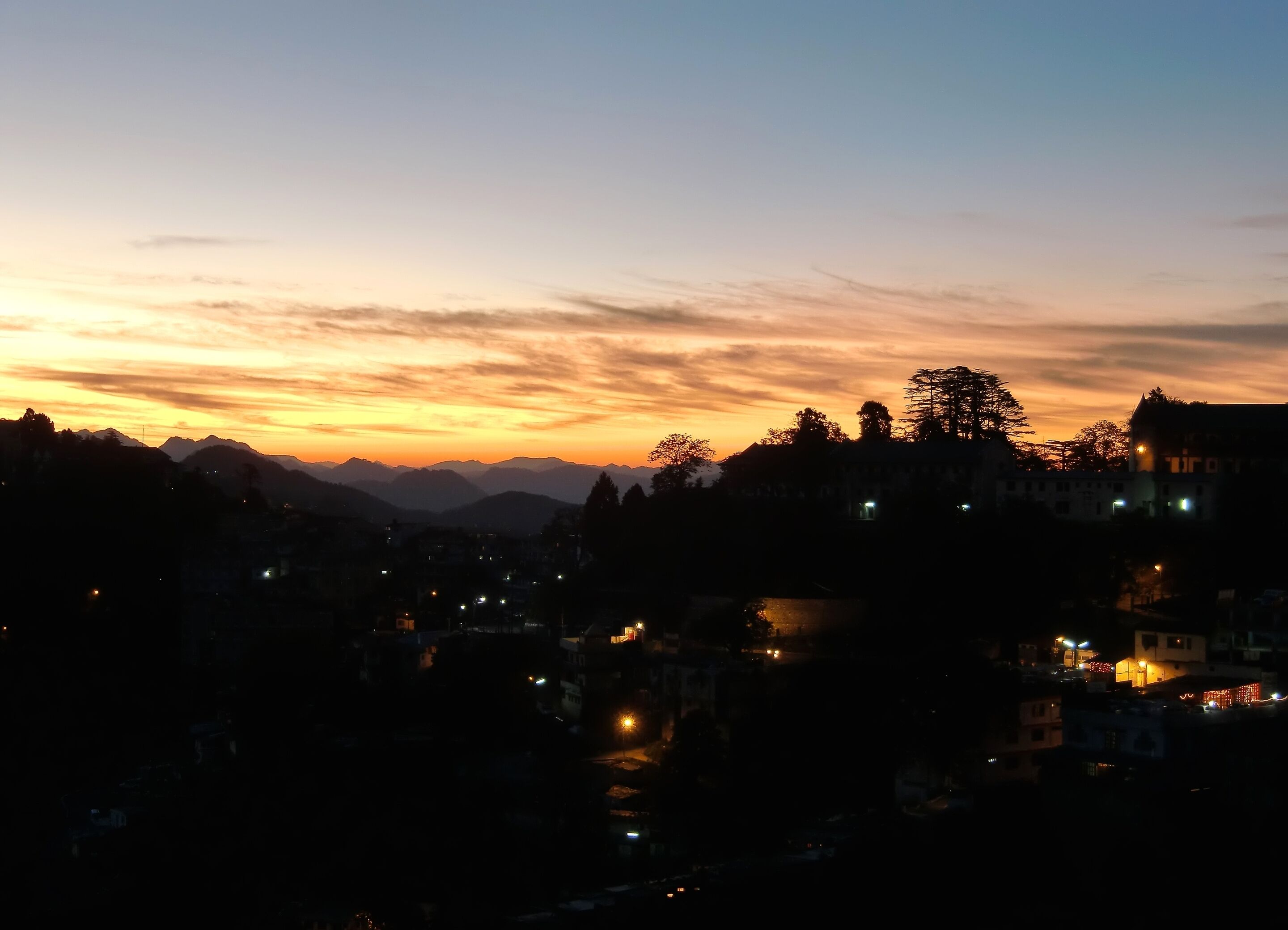 A cityscape at dusk with mountains in the background.