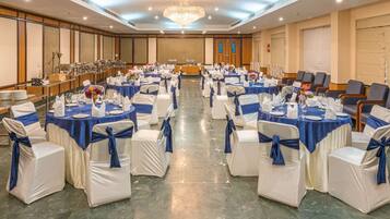 A banquet hall with round tables, white chairs, and blue sashes.